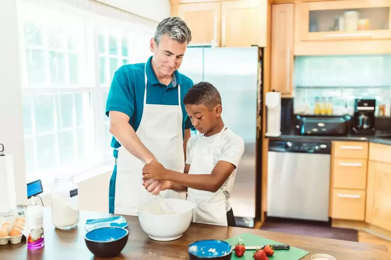 Foster Dad helping a child in the kitchen.