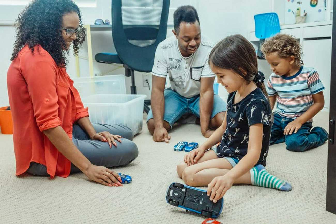 Two foster parents playing with two foster kids on the floor