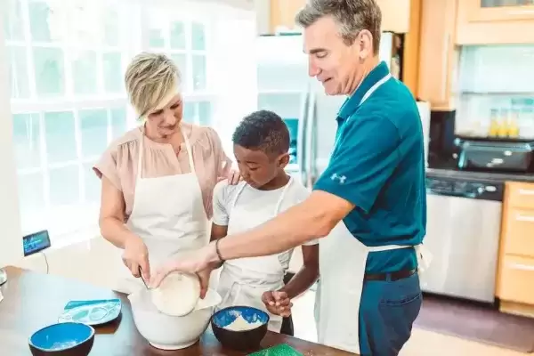 foster parents teaching a child to cook in Kitchen