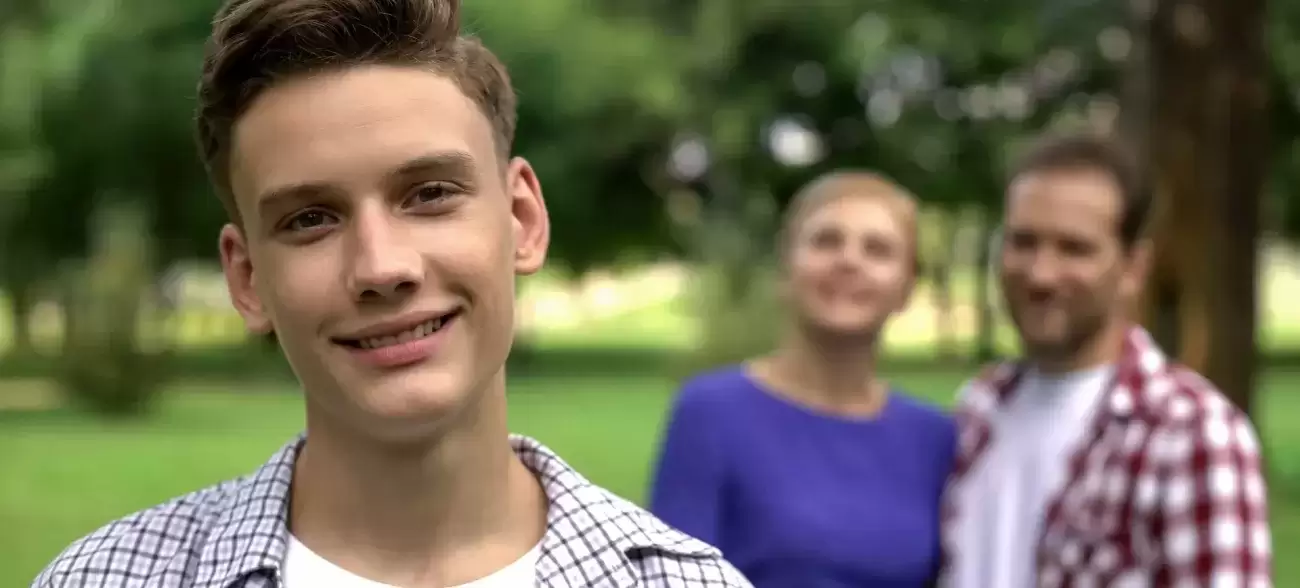 Teenager with foster parents standing in background
