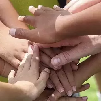 Lots of kids hands on top of each others hands 